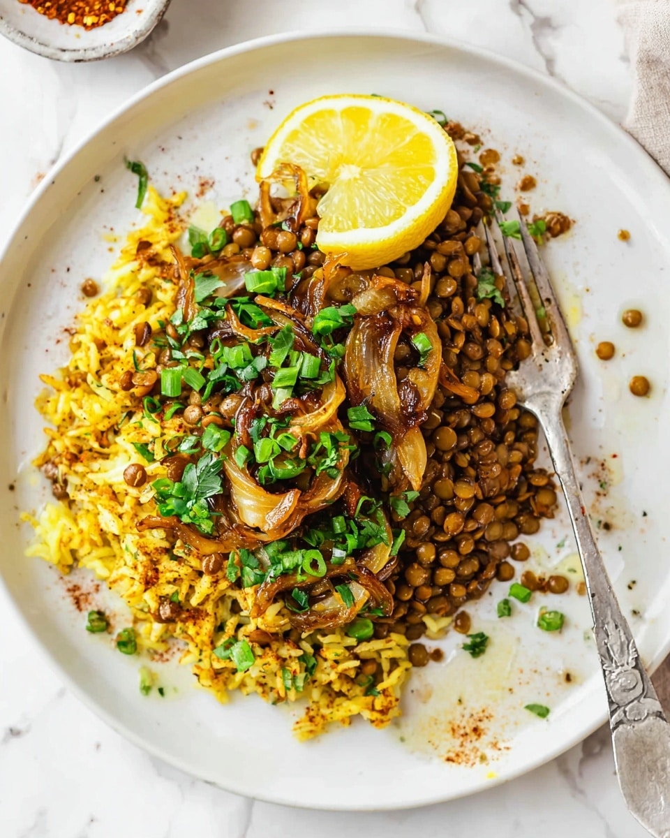 A white plate holds a serving of a mixed dish with three visible layers: a base layer of brown lentils, a middle layer of yellow rice mixed with the lentils, and a topping of cooked caramelized onions with chopped bright green scallions scattered on top. On the upper side of the plate, a lemon wedge is placed partially on the food. To the right of the plate, there is a silver fork resting on the edge. The plate sits on a white marbled surface with some small specks of spice and a small puddle of oil around the food. photo taken with an iphone --ar 4:5 --v 7