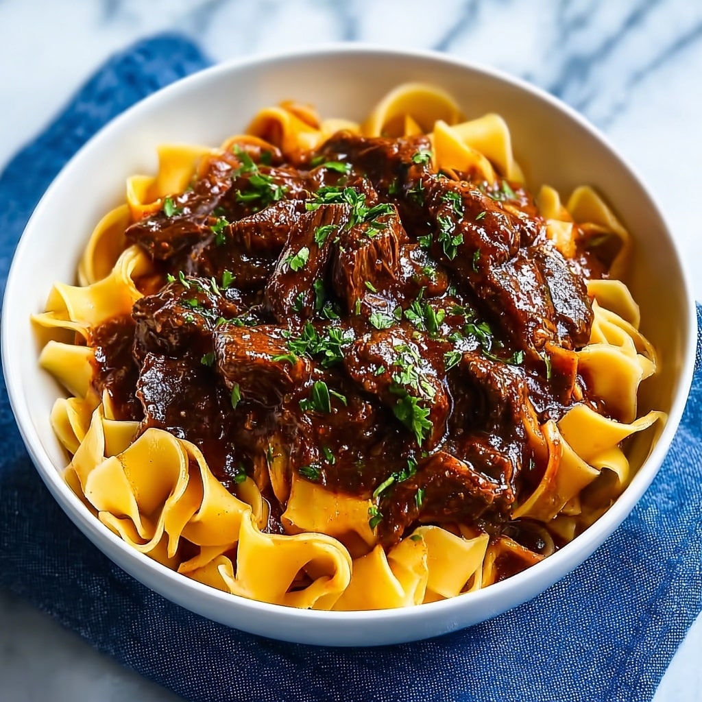 A close-up view of a white bowl filled with three main layers: the bottom layer has thick, yellowish flat noodles that look soft and smooth; the middle layer consists of tender, dark brown beef chunks covered in a rich, glossy sauce; the top layer is sprinkled with small green herb pieces adding fresh color contrast. The dish looks moist and savory against a white marbled surface. photo taken with an iphone --ar 4:5 --v 7