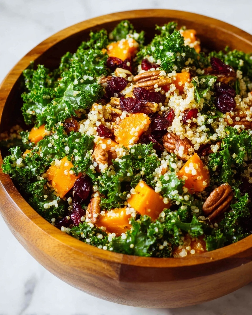 A close-up photo of a wooden bowl filled with a colorful quinoa salad. The salad has several layers including bright green curly kale, small light beige quinoa grains, orange roasted butternut squash cubes, red dried cranberries, and small white cheese crumbles scattered throughout. There are also some brown pecan nuts and chickpeas mixed in. A wooden spoon is placed inside the bowl, resting on the white marbled surface below. photo taken with an iphone --ar 4:5 --v 7