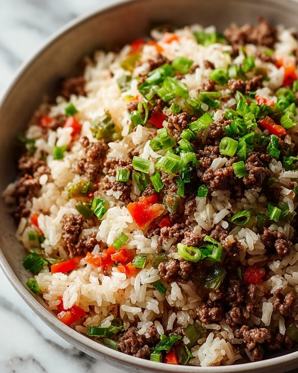 The image shows a close-up of a bowl filled with a mixed dish. The bottom layer is white rice with a slightly sticky texture. The second layer consists of cooked minced brown beef scattered evenly throughout the rice. Mixed in are small chopped red bell pepper pieces that add bright pops of red color. There are also green chopped vegetables, including sliced green onions and leafy herbs, spread on top and throughout the dish. The bowl holding the food is white with a smooth finish, placed on a white marbled surface. photo taken with an iphone --ar 4:5 --v 7