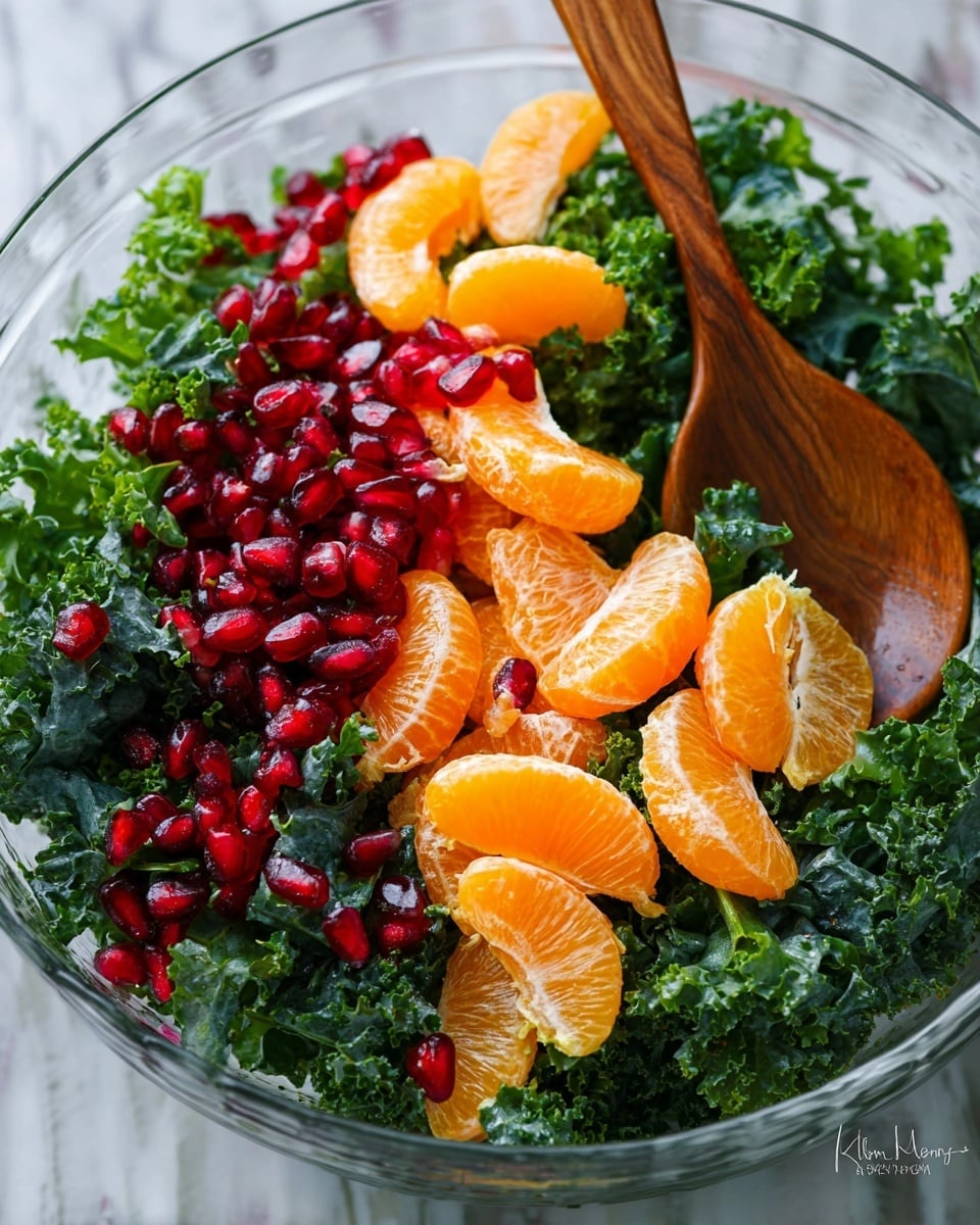 A wooden bowl filled with a fresh salad consisting of three main layers: a base of dark green curly kale leaves with a rough texture, topped with bright orange mandarin segments that have a smooth and glossy surface, and sprinkled all over with shiny red pomegranate seeds and light green pumpkin seeds. The salad has a mix of colors and textures spread evenly, with a silver serving spoon partially visible on the right side. The scene is set on a white marbled texture with a glass jar of honey and lemon slices blurred in the background, along with a folded red cloth at the bottom edge. photo taken with an iphone --ar 4:5 --v 7