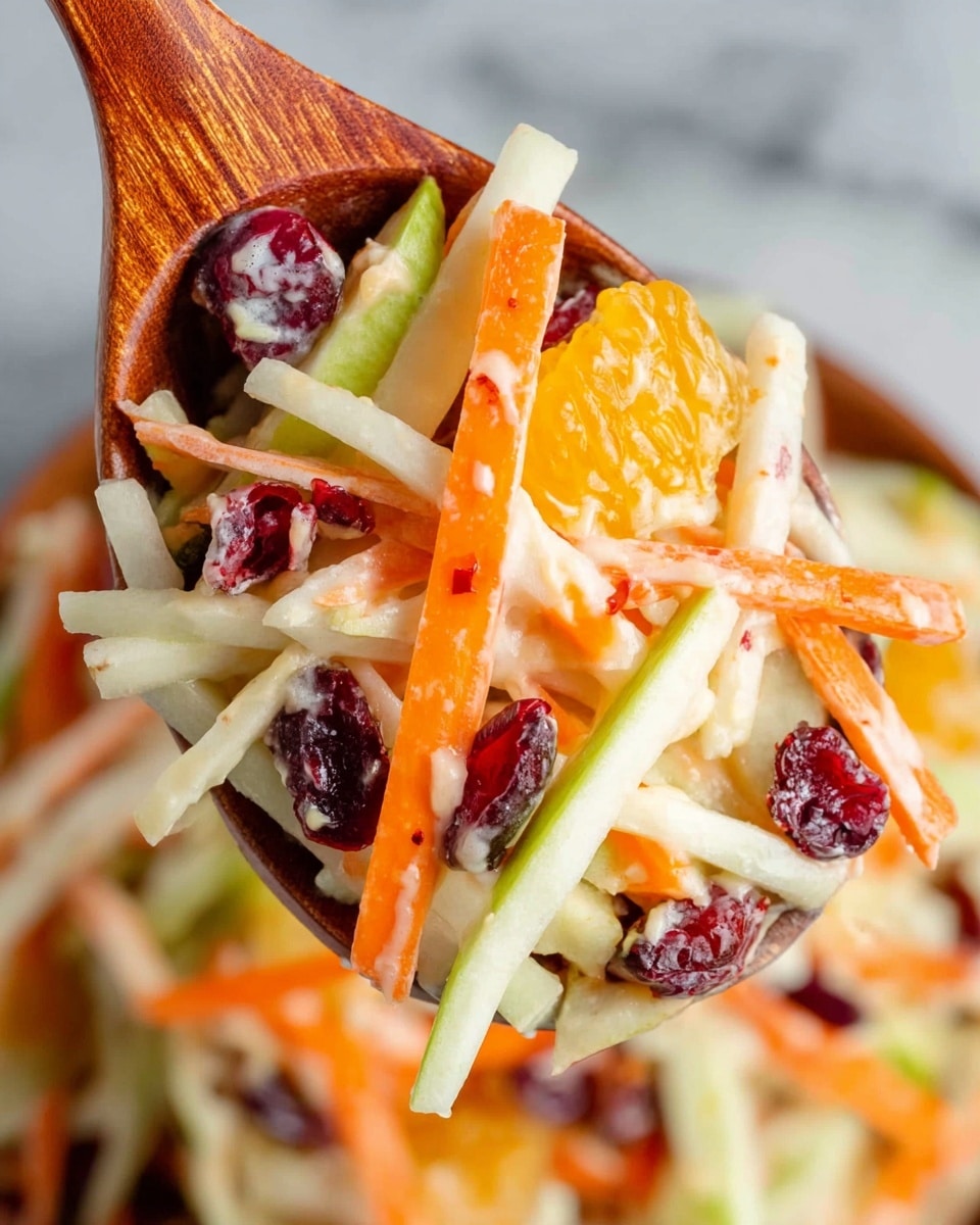 A close-up view of a wooden spoon holding a colorful fruit and vegetable salad with thin slices and sticks. The salad includes bright orange carrot sticks, pale green apple slices with a hint of red skin, white apple or jicama sticks, shiny dark red dried cranberries, and small juicy orange segments, all mixed and lightly coated with a creamy dressing. The background shows more of the salad with the same mix of colors, placed on a white marbled textured surface. Photo taken with an iphone --ar 4:5 --v 7
