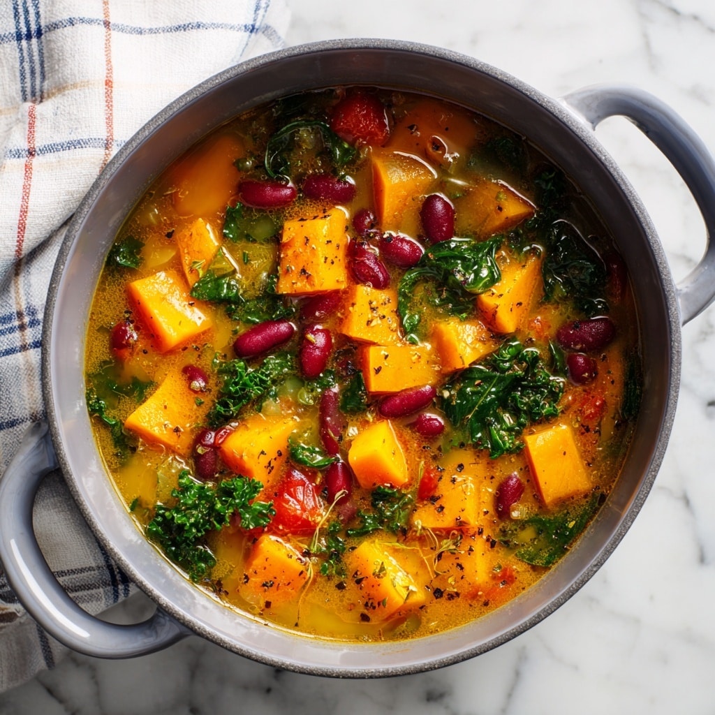A close-up view of a thick stew served in a white round pot with two handles, filled with large chunks of orange and yellow vegetables, deep red kidney beans, and bright green leafy herbs, all mixed in a rich yellow broth dotted with black pepper and herbs. The pot is placed on a white marbled surface, next to a folded checkered cloth with green, red, and white colors, contributing a cozy, rustic feel. photo taken with an iphone --ar 4:5 --v 7