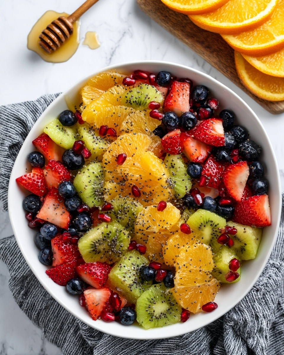 A white bowl filled with a colorful fruit salad showing three main layers: the bottom layer has bright orange slices with a slightly rough texture, the middle layer is full of red strawberries cut into halves and quarters showing their juicy interior, and the top layer has green kiwi pieces with visible black seeds, dark blue blueberries, and scattered shiny red pomegranate seeds. The fruit pieces are fresh and vibrant, sitting on a gray cloth with white stripes on a white marbled surface. In the background, a wooden board holds a honey dipper and a halved orange. photo taken with an iphone --ar 4:5 --v 7