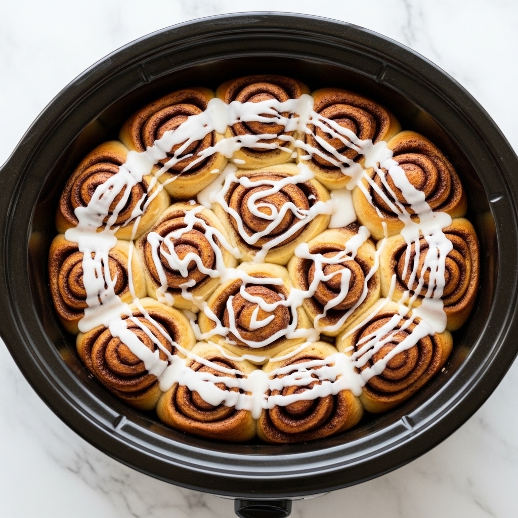 The image shows a close-up of many small, golden-brown pieces of soft dough coated in a creamy white glaze with specks of brown cinnamon sprinkled on top. The dough pieces are layered closely together in a round black pot, with some glaze pooling slightly between the pieces. The texture of the dough looks soft and slightly spongy, while the glaze appears smooth and slightly shiny, creating a rich and sweet appearance. photo taken with an iphone --ar 4:5 --v 7