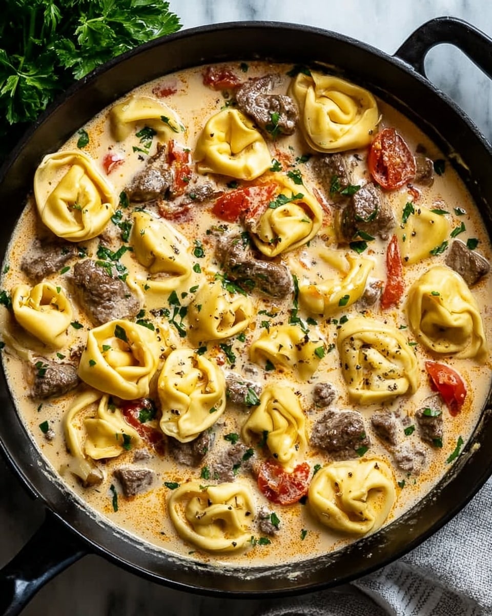 The dish is served in a black cast iron pot placed on a white marbled surface. It has about three main layers: the bottom cream sauce is light yellow with a smooth texture; next are chunks of browned beef strips and small pieces of reddish tomatoes scattered around; the top layer shows ten plump yellow tortellini evenly spread and covered lightly by the creamy sauce. The cream sauce also has small green parsley pieces sprinkled on top along with black pepper for seasoning. On the side near the pot, there is a bunch of fresh green herbs adding a fresh touch to the scene. photo taken with an iphone --ar 4:5 --v 7