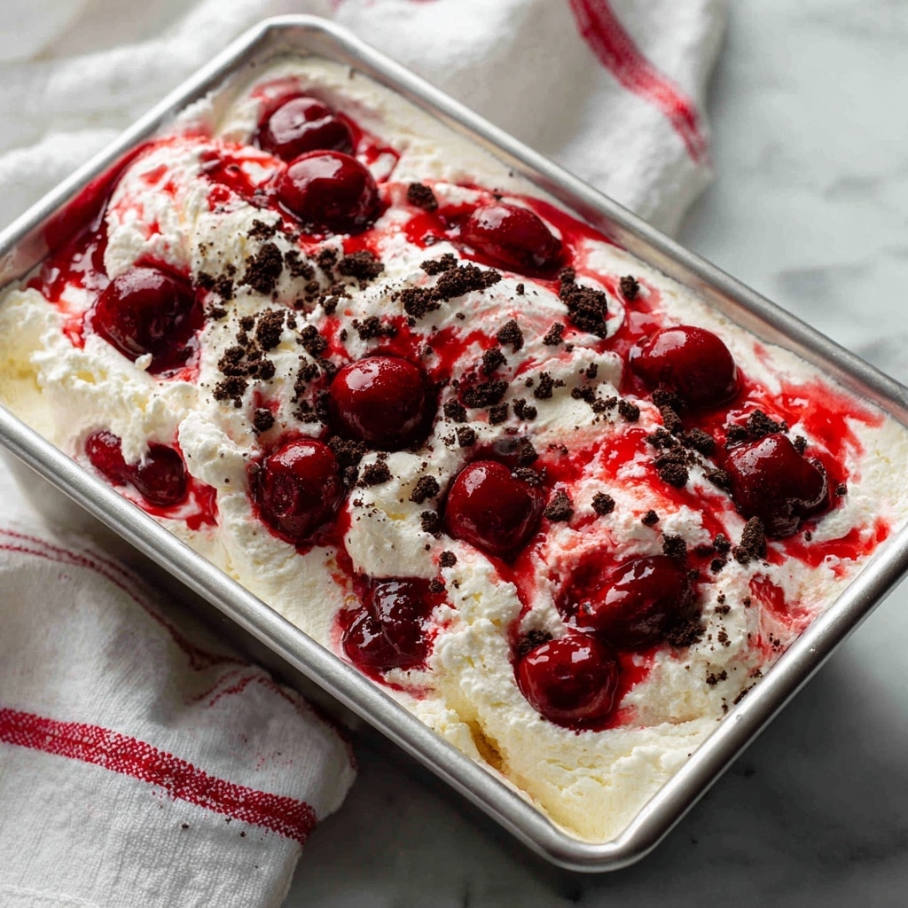 A clear glass bowl filled with a mix of layered dessert showing white whipped cream swirled with bright red cherry sauce and interspersed with dark brown crushed cookie crumbs. The dessert has about three visible layers: the bottom layer of crushed dark cookies, a middle layer of white cream with red cherry pieces, and the top layer showing a mix of all three ingredients swirled together. The bowl sits on a white marbled surface next to a beige cloth with red stripes. photo taken with an iphone --ar 4:5 --v 7