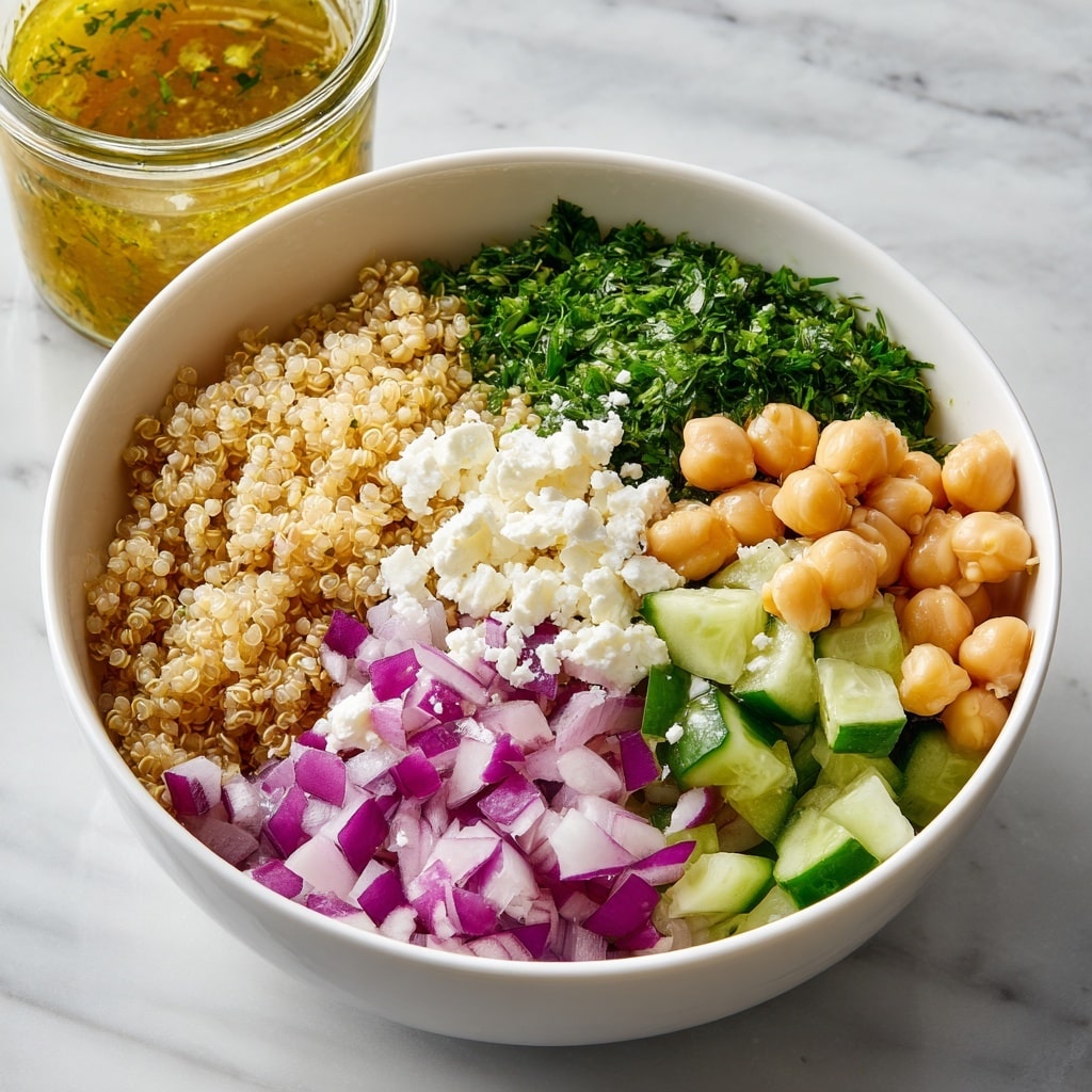 A white bowl filled with six different layers: chopped green cucumber pieces at the bottom right, finely diced light purple onions next to them, round light brown chickpeas at the left, curly dark green parsley in the middle back, light beige cooked quinoa near the top right, and crumbly white cheese on the right side over the cucumber. The bowl is placed on a wooden surface with a blurry glass jar of yellowish dressing and lemon wedges in the background on a white marbled surface. photo taken with an iphone --ar 4:5 --v 7