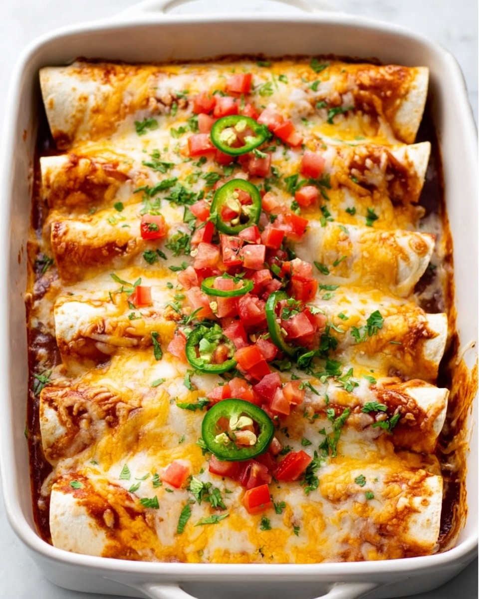 A white rectangular baking dish filled with six rolled enchiladas, each covered in a golden melted cheese layer that appears gooey and slightly browned on the edges. The top layer is scattered with small diced red tomatoes and thin slices of green jalapeño peppers. There are bits of green herbs sprinkled evenly over the dish, adding a fresh touch. The enchiladas rest closely packed side by side, showing soft, slightly browned tortillas under the cheese. The white marbled surface beneath the dish gives a clean, bright look. Photo taken with an iphone --ar 4:5 --v 7