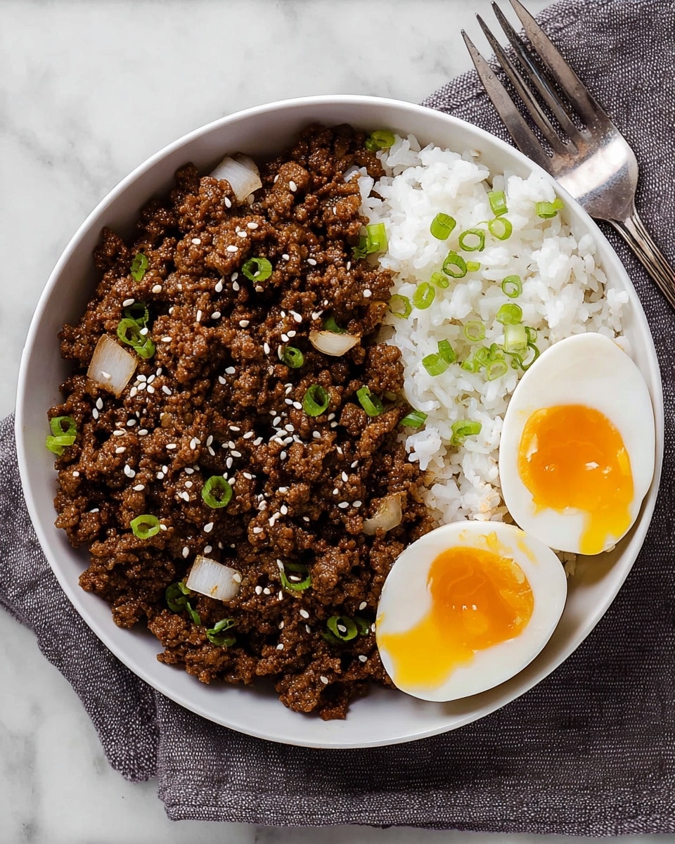 A white bowl on a white marbled surface holds three main parts: on the left, a big pile of brown cooked ground beef mixed with small pieces of onion, sprinkled with white sesame seeds and chopped green onions; on the right, a portion of white steamed rice with a few bits of green onion on top; and near the bottom right side of the rice, two halves of a soft-boiled egg with white outer layer and bright yellow yolk slightly oozing out. The bowl is placed on a grey cloth, and a silver fork is set to the right side of the bowl. photo taken with an iphone --ar 4:5 --v 7