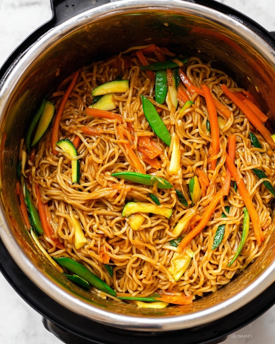 The image shows a close-up of a pot filled with cooked noodles mixed with a variety of vegetables. The noodles are light brown and coated in sauce, forming a dense layer inside the pot. Mixed throughout are several vegetables: bright orange carrot sticks, green snap peas, green zucchini slices with yellow edges, and light yellow squash pieces. The vegetables are cut in thin strips and chunks and are evenly spread among the noodles, adding texture and color contrast. The shiny metal rim of the pot frames the food, and the inner pot surface has sauce marks. The background features a white marbled texture. photo taken with an iphone --ar 4:5 --v 7